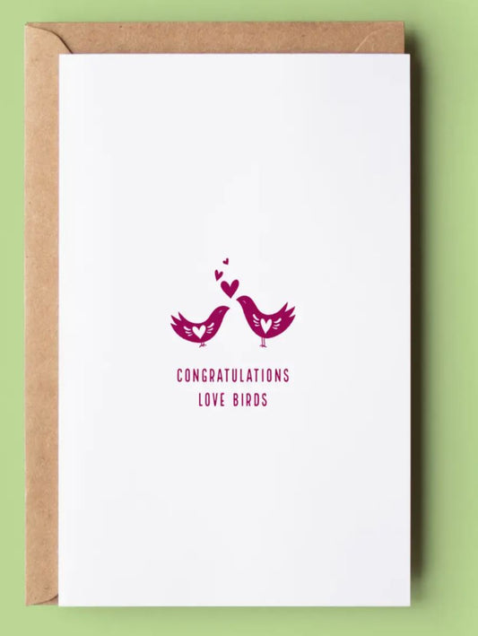 This is a white card with an illustration of two bird in red with hearts coming out of their beaks, it reads, congratulations love birds.