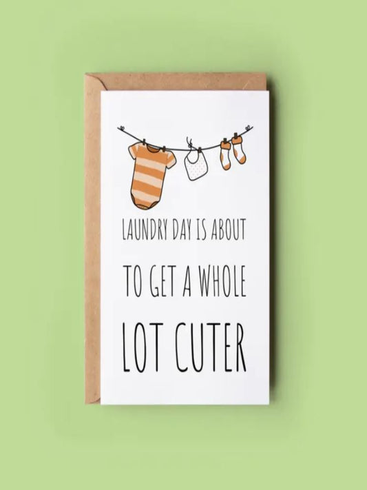 This card shows a drawing of a baby's laundry on the line. tiny socks, a bib, a babygrow. It says 'laundry day is about to get a whole lot cuter'