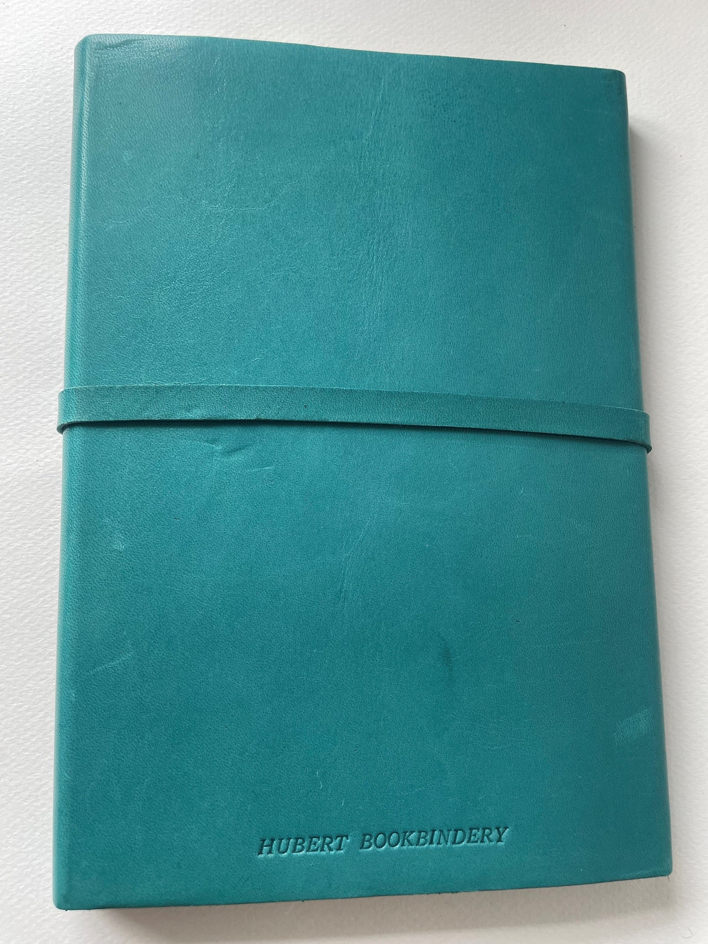 The back of a teal notebook with the word Hubert Bookbindery on the bottom.