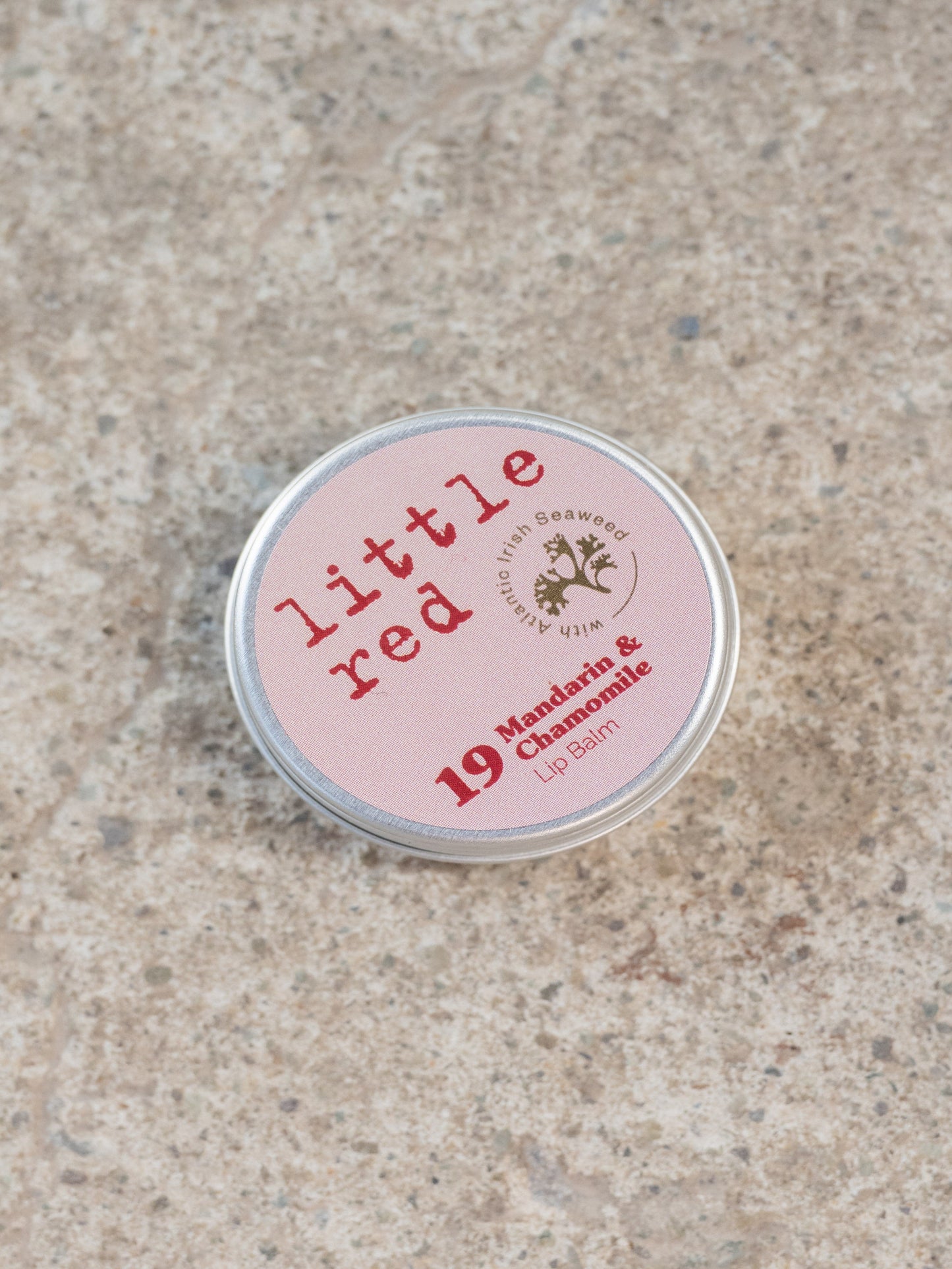Small pink tin labeled 'little red' on a textured beige surface