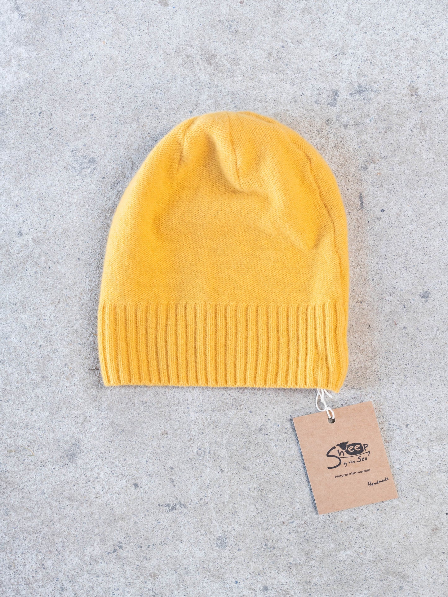 Yellow beanie with a brand tag on a gray surface