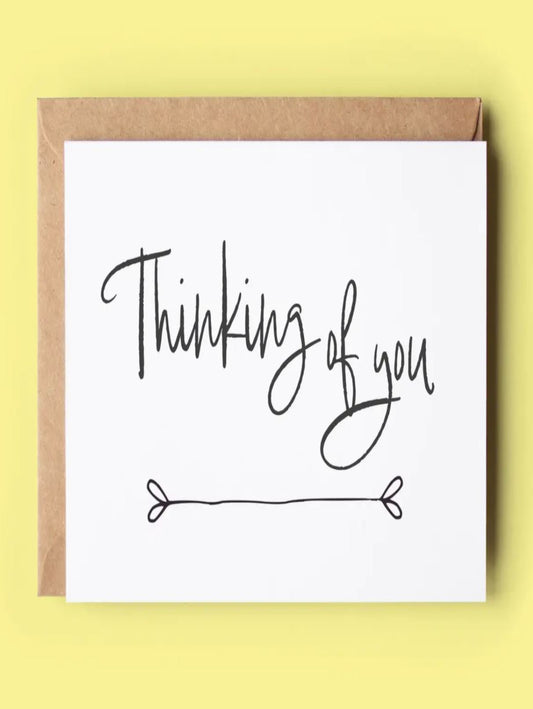 This depicts a white card that has the words thinking of you on it.
