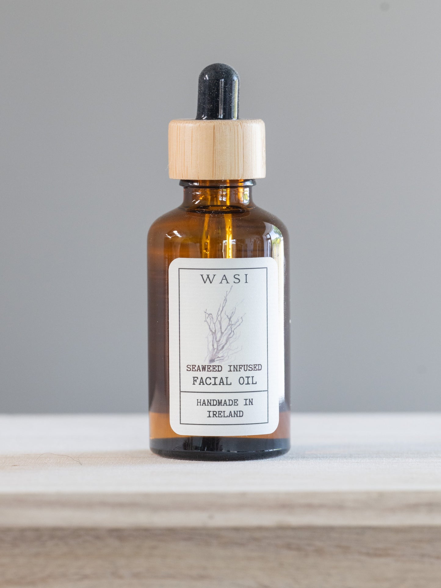 Amber glass bottle with wooden dropper labeled 'WASI'. This is seaweed infused facial oil handmade in Ireland.