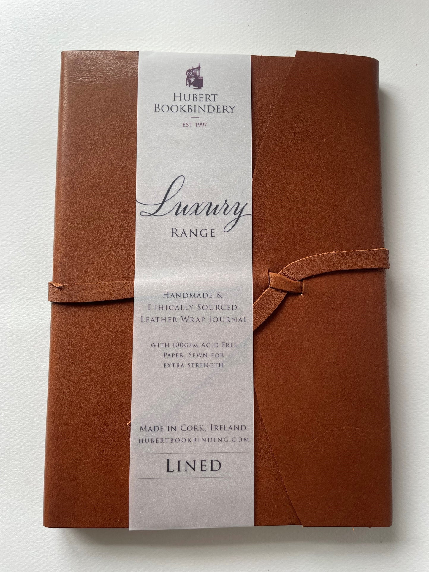 a brown leather bound note book that is lined, it's handmade with a label that says Hubert Bookbindery.
