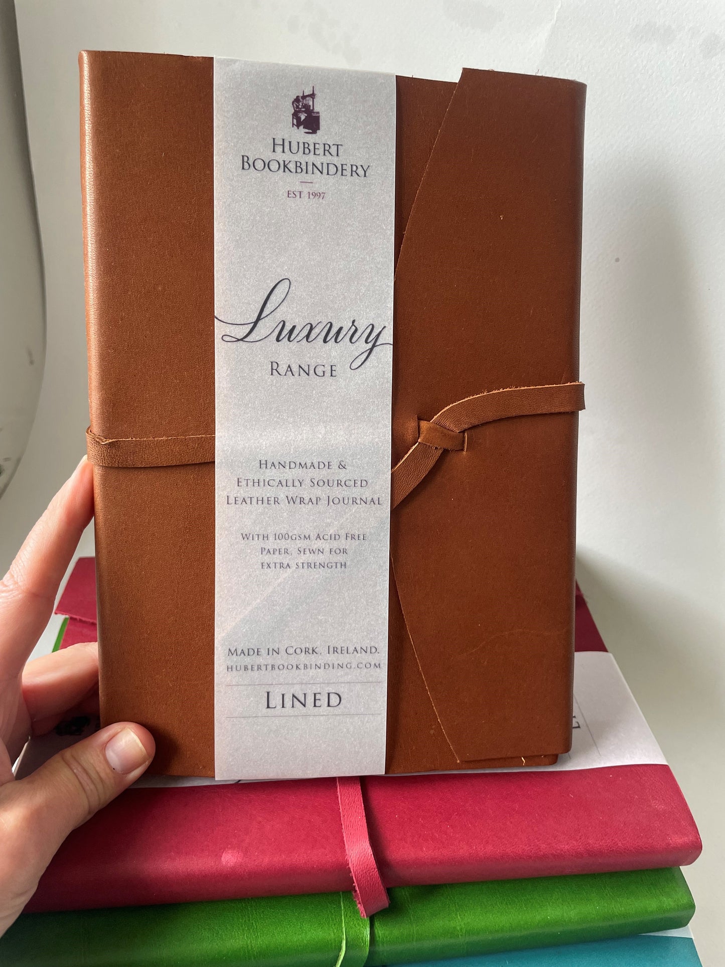 a brown leather bound note book that is lined, it's handmade with a label that says Hubert Bookbindery.