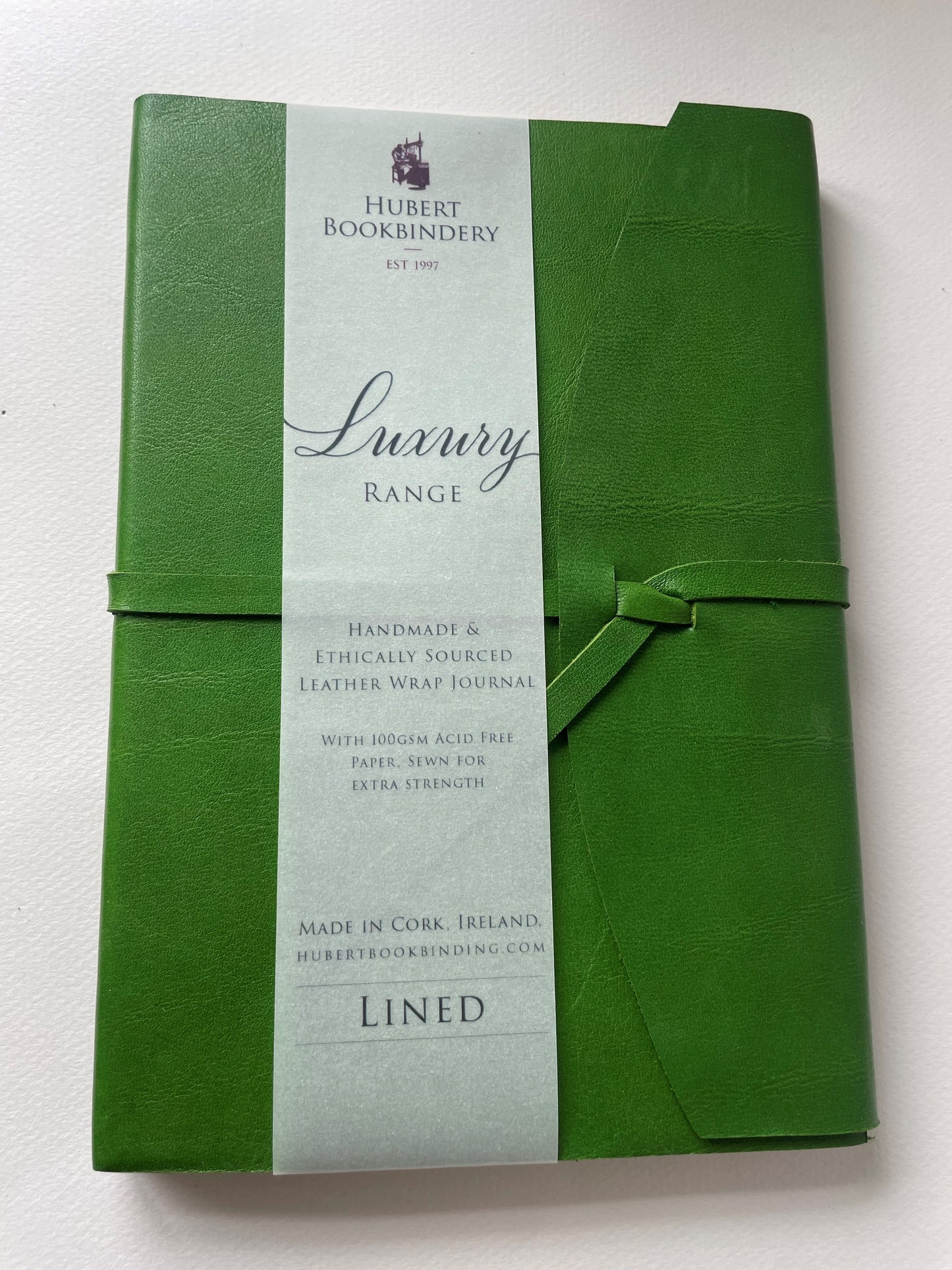 a green leather bound note book that is lined, it's handmade with a label that says Hubert Bookbindery.