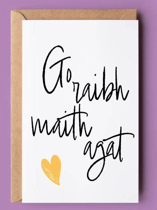 white card with the Gaelic 'go raibh maith agat' which means thank you in Irish . THere is a yellow heart also.