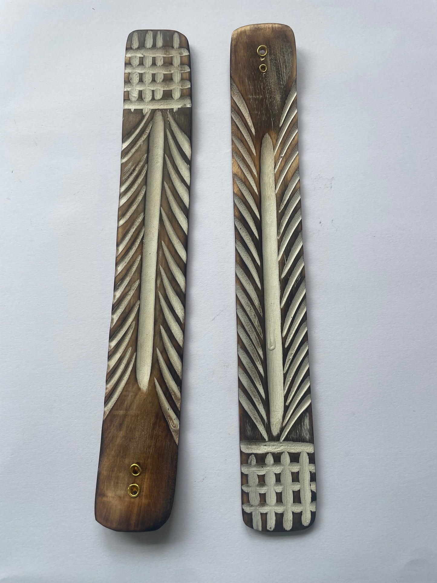 This photo is of two incense stick holders side by side. It shows the brown and white groves of an aztec design and there are two holes where you can place your incense.