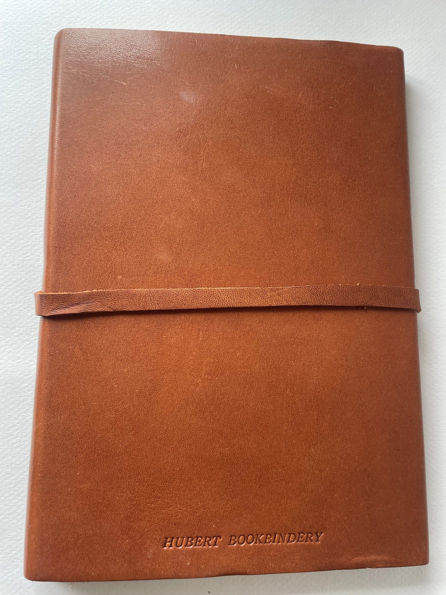 The back of a brown leather notebook with the word Hubert Bookbindery on the bottom.