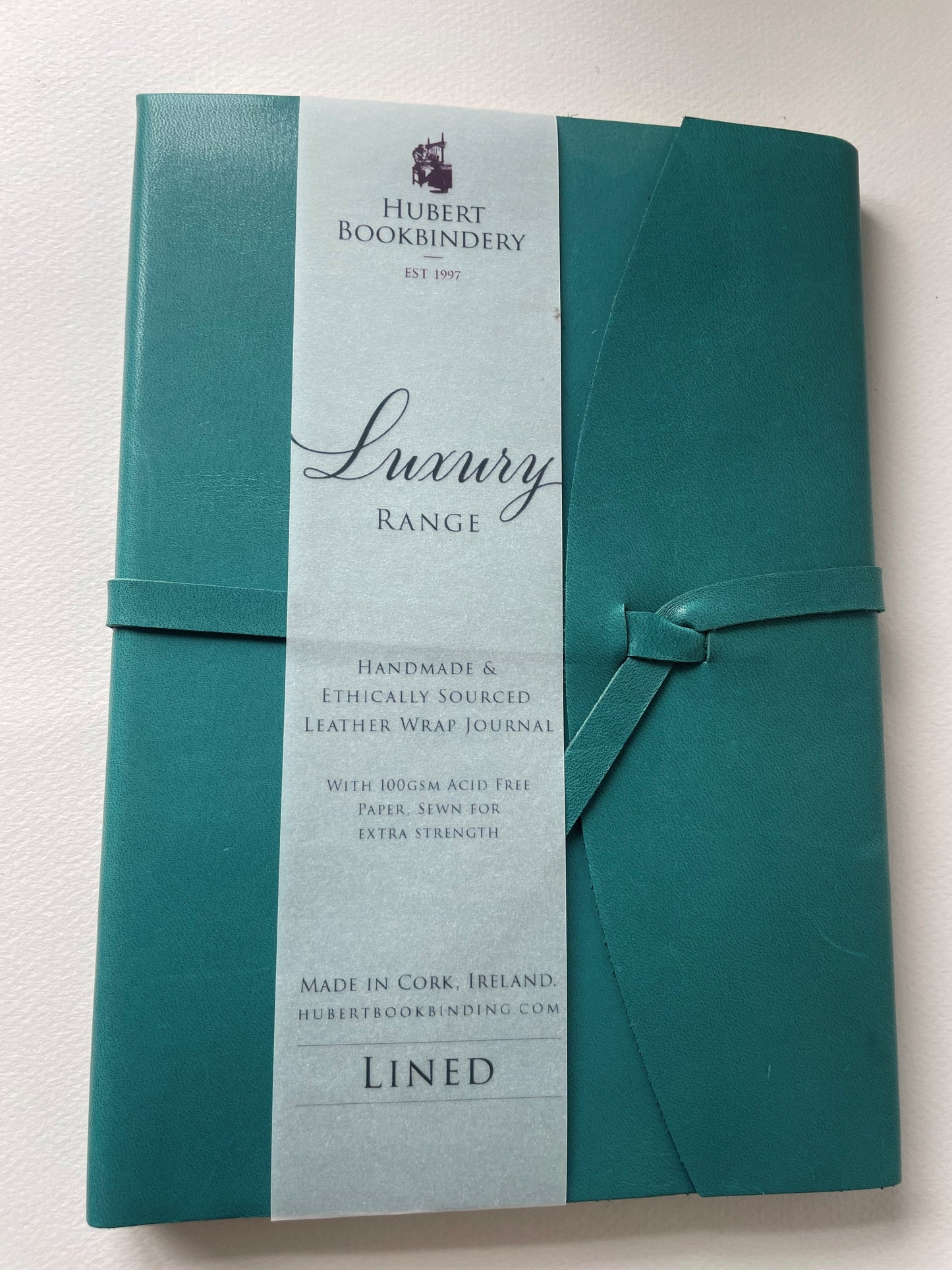 The front of a teal luxury notebook that is lined, it is by Hubert Bindery