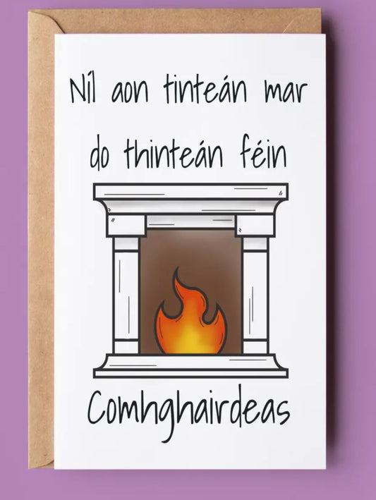 This card has a picture of a fireplace and is Irish, it says Nil aon tintean mar do thintean fein, comhghairdeas, this means there's no firelplace like your own fireplace and congratulations.