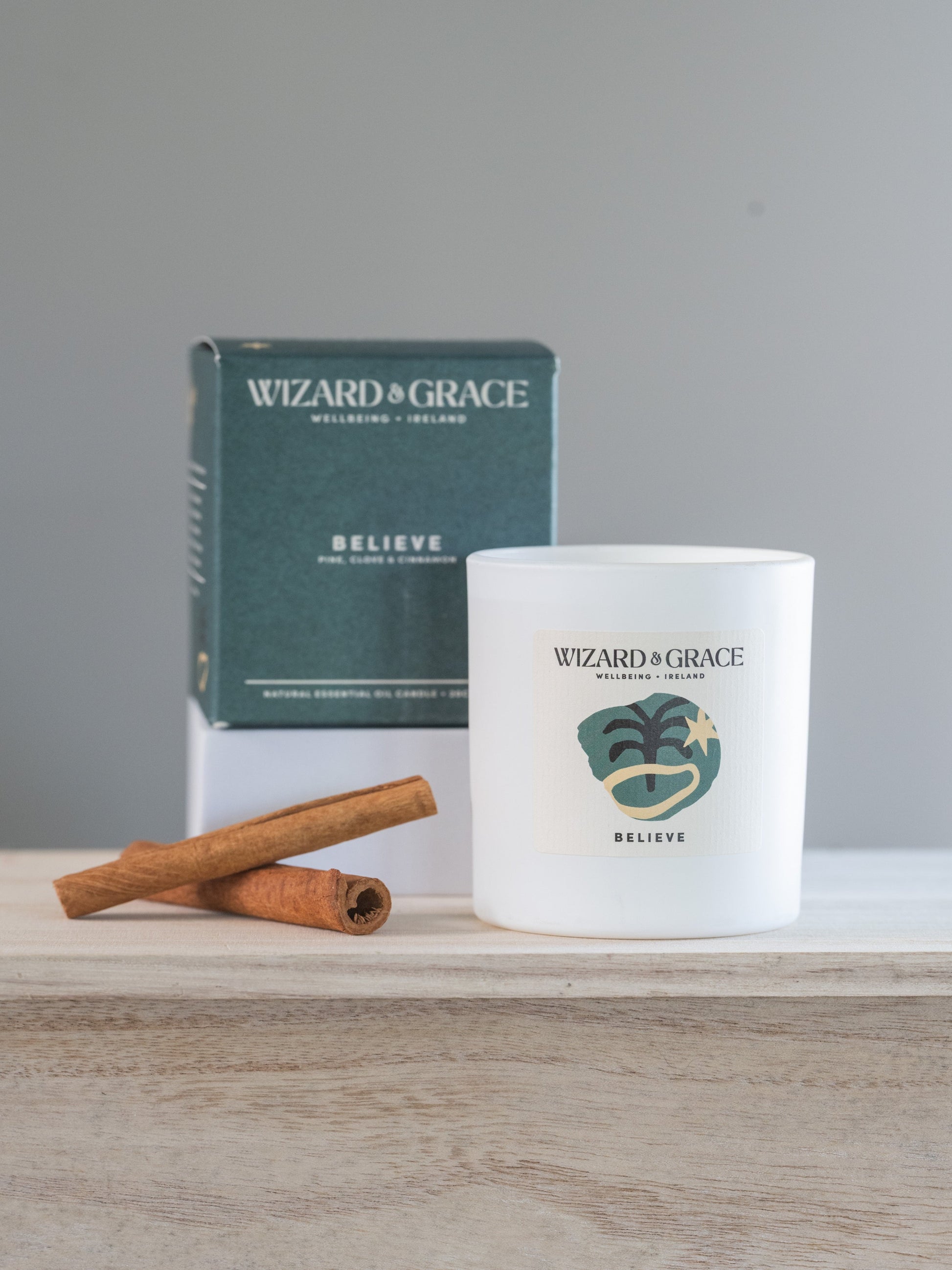 A picture of a candle with two cinnamon sticks next to it. 