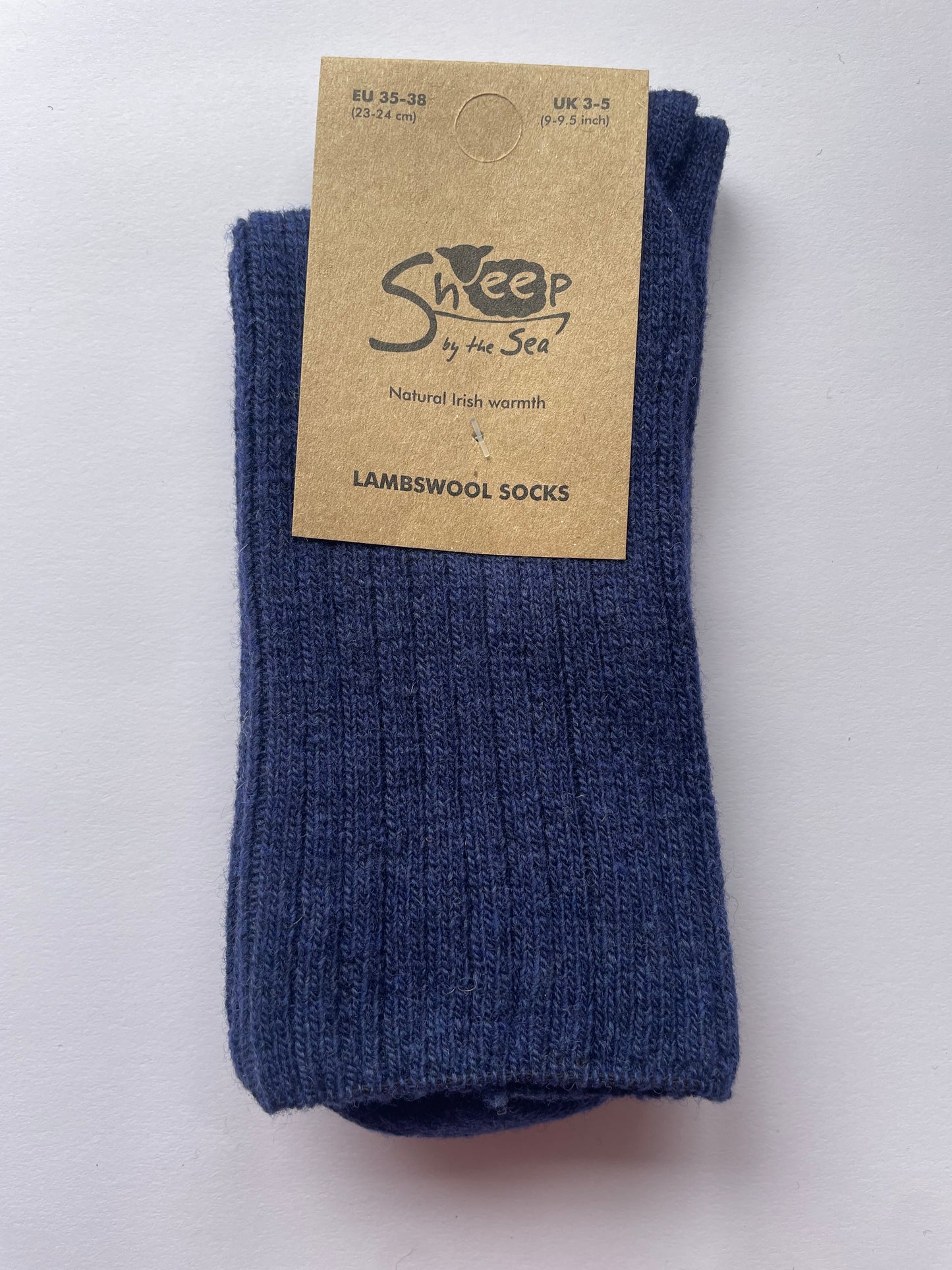 blue socks with a brown label that says sheep by the sea, natural Irish warmth, lambs wool socks. 