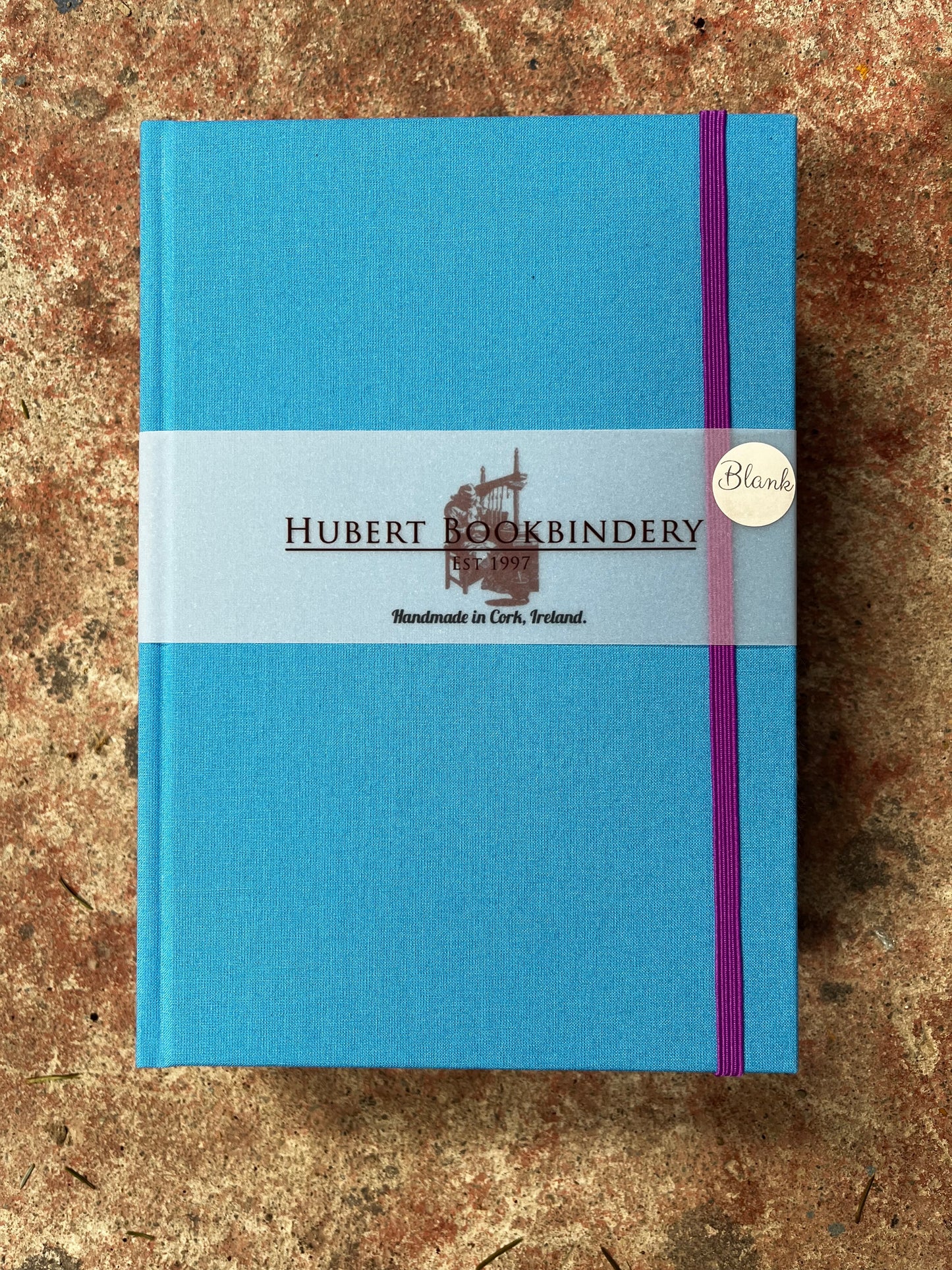 Blue notebook with Hubert Bookbindery branding on a textured surface