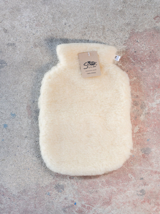 White hot water bottle with a label on a textured surface