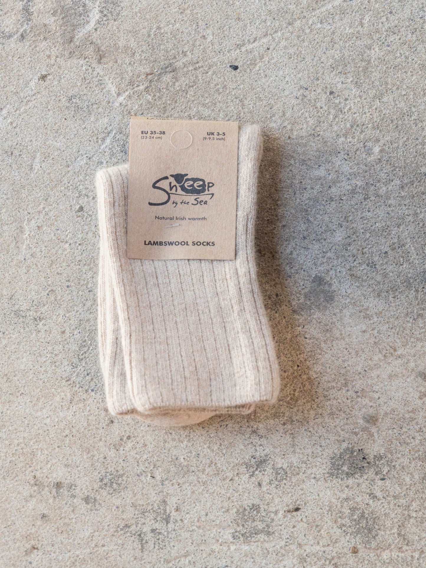 Pair of white socks with a 'Sheep on the Street' label on a textured gray surface