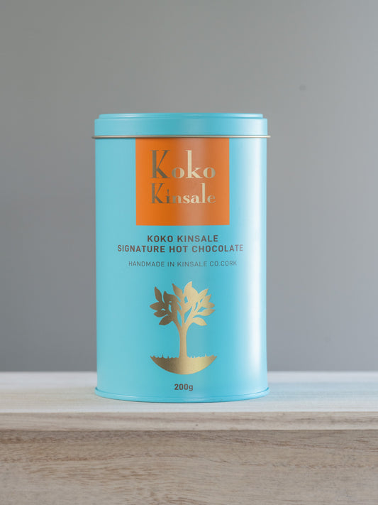 Koko Kinsale signature hot chocolate canister on a wooden surface with a gray background
