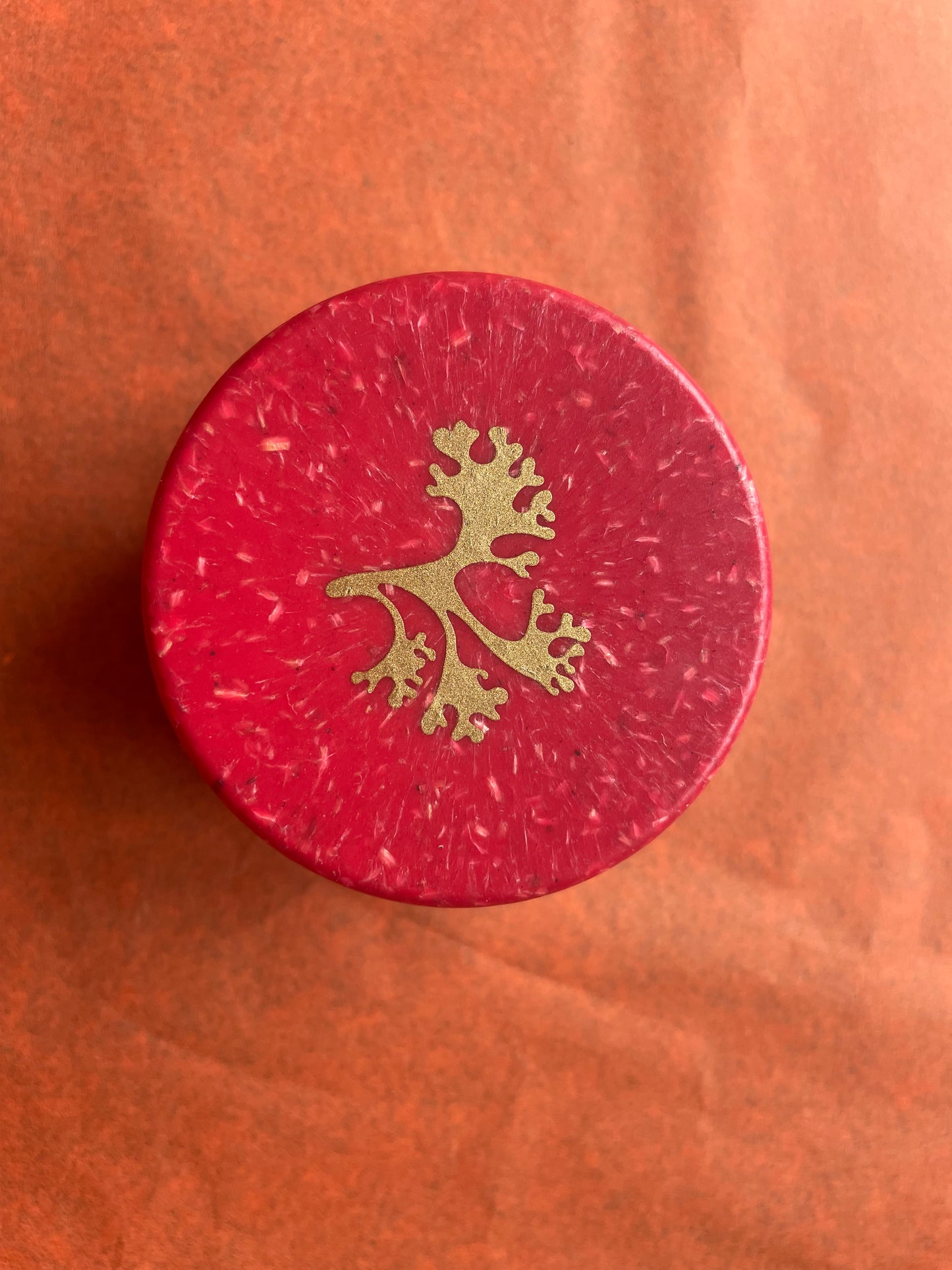 This shows the red lid of the handcream with a hold tree on the front of it. 