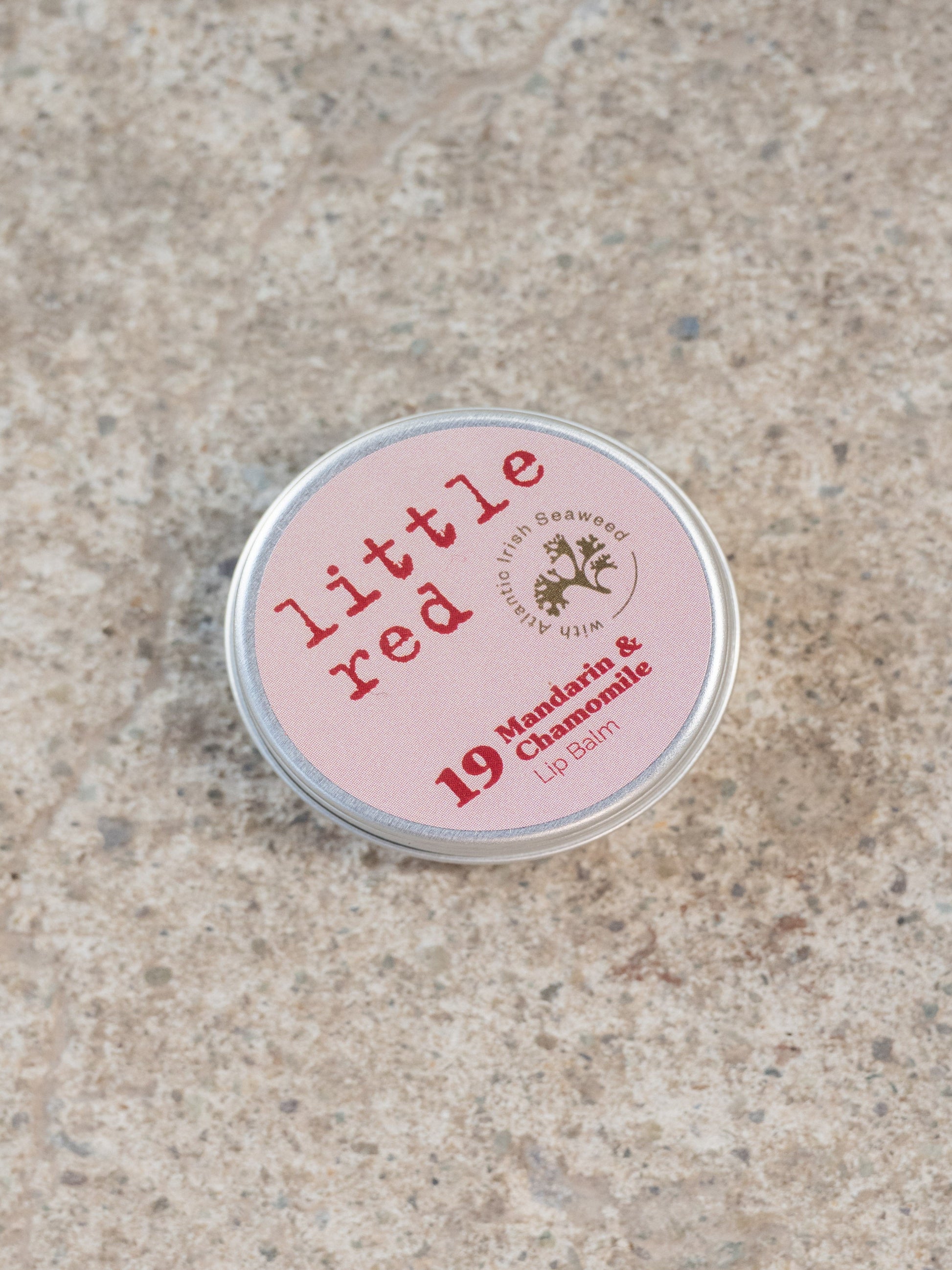 Small pink tin labeled 'little red' on a textured beige surface