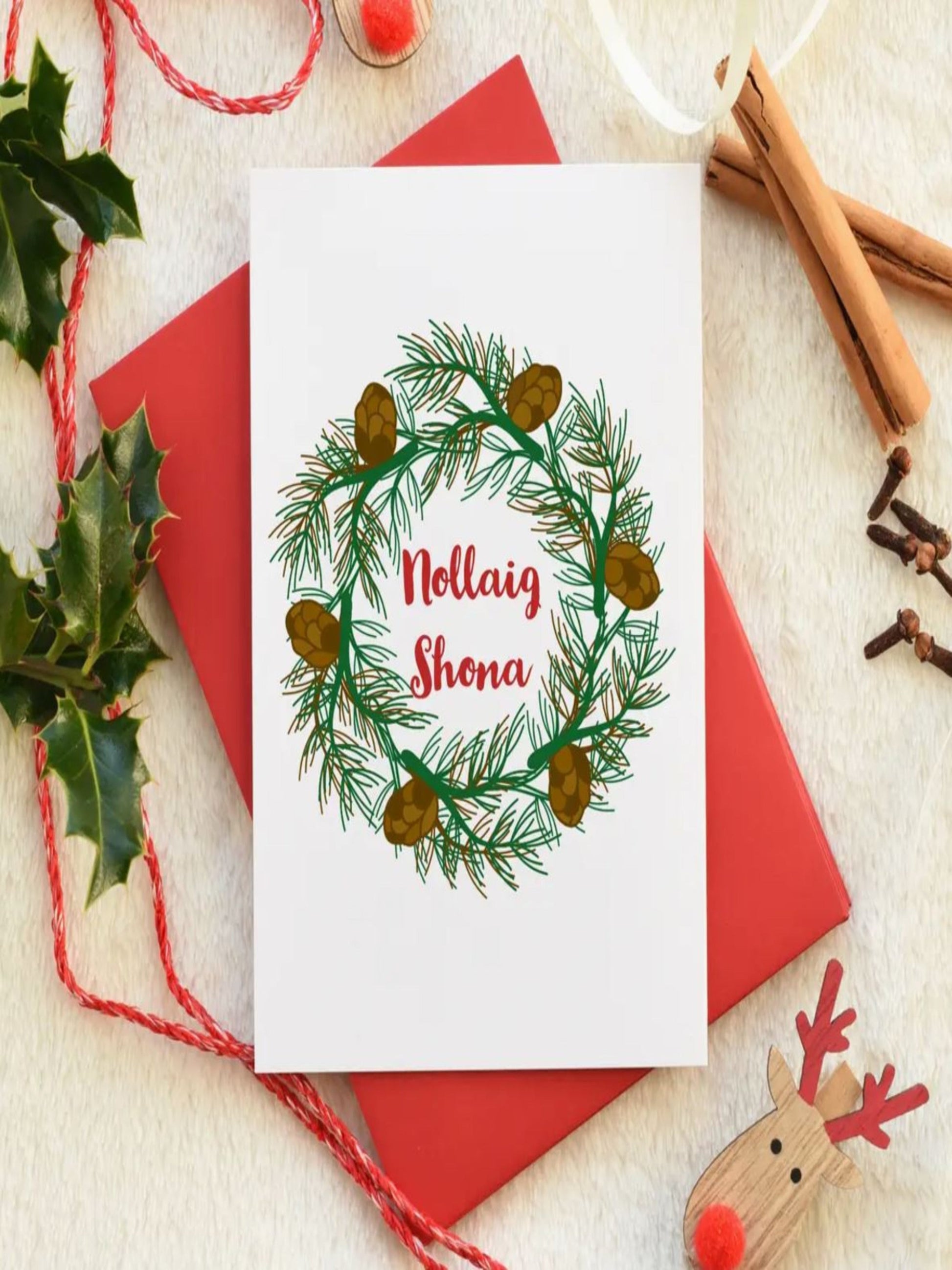 This card is a drawing of a wreath and in the middle is says 'NOLLAIG SHONA' which is the Irish for Happy Christmas. The writing is in red and the wreath is in green. There's also a red envelope. 