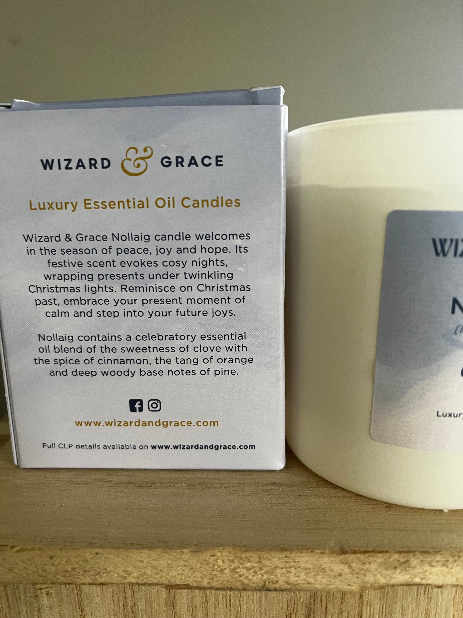 Candle with packaging displaying 'Wizard & Grace' branding on a wooden surface.