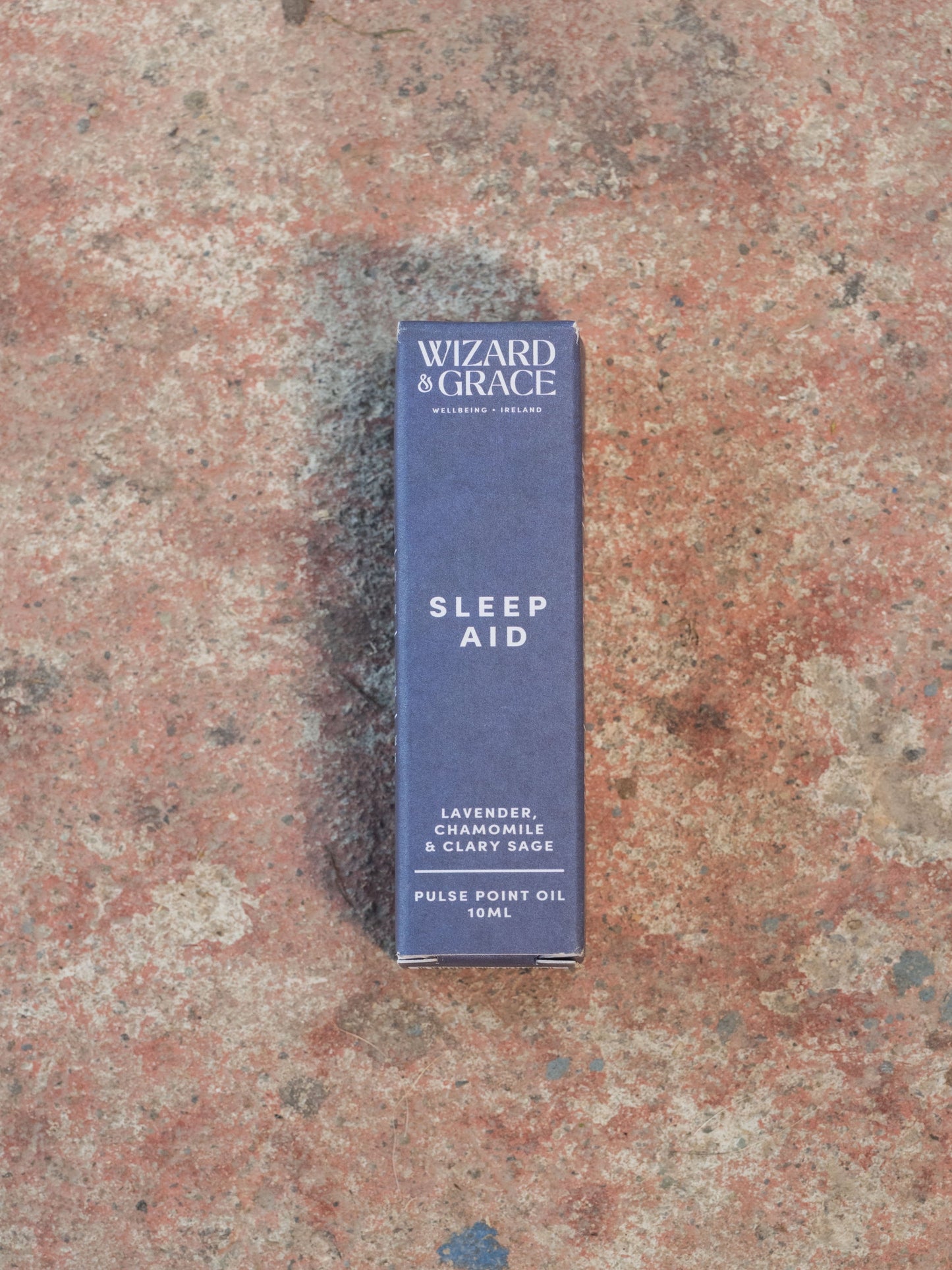 Blue box labeled 'Sleep Aid' by 'Wizard of Grace' on a textured surface