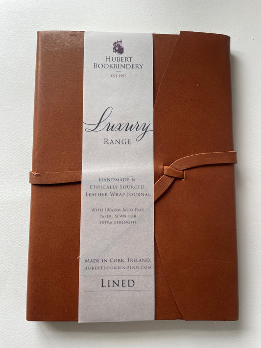 a brown leather bound note book that is lined, it's handmade with a label that says Hubert Bookbindery. 