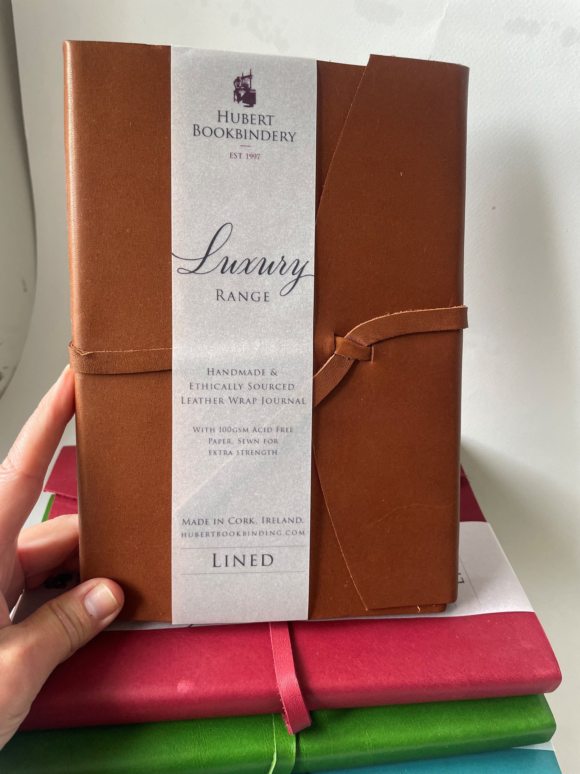 a brown leather bound note book that is lined, it's handmade with a label that says Hubert Bookbindery. 