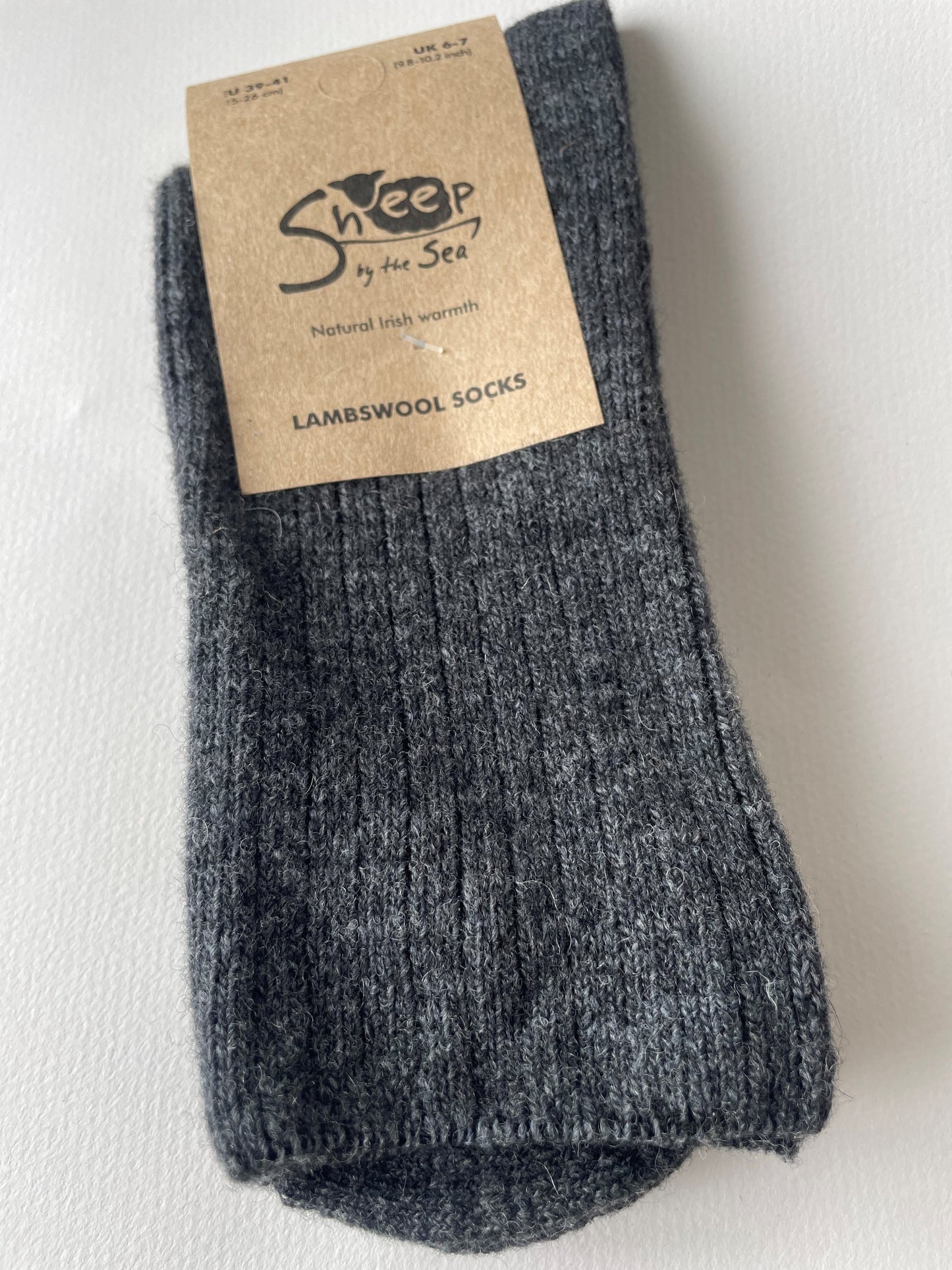 Charcoal socks with a brown label that says sheep by the sea, natural Irish warmth, lambs wool socks. 