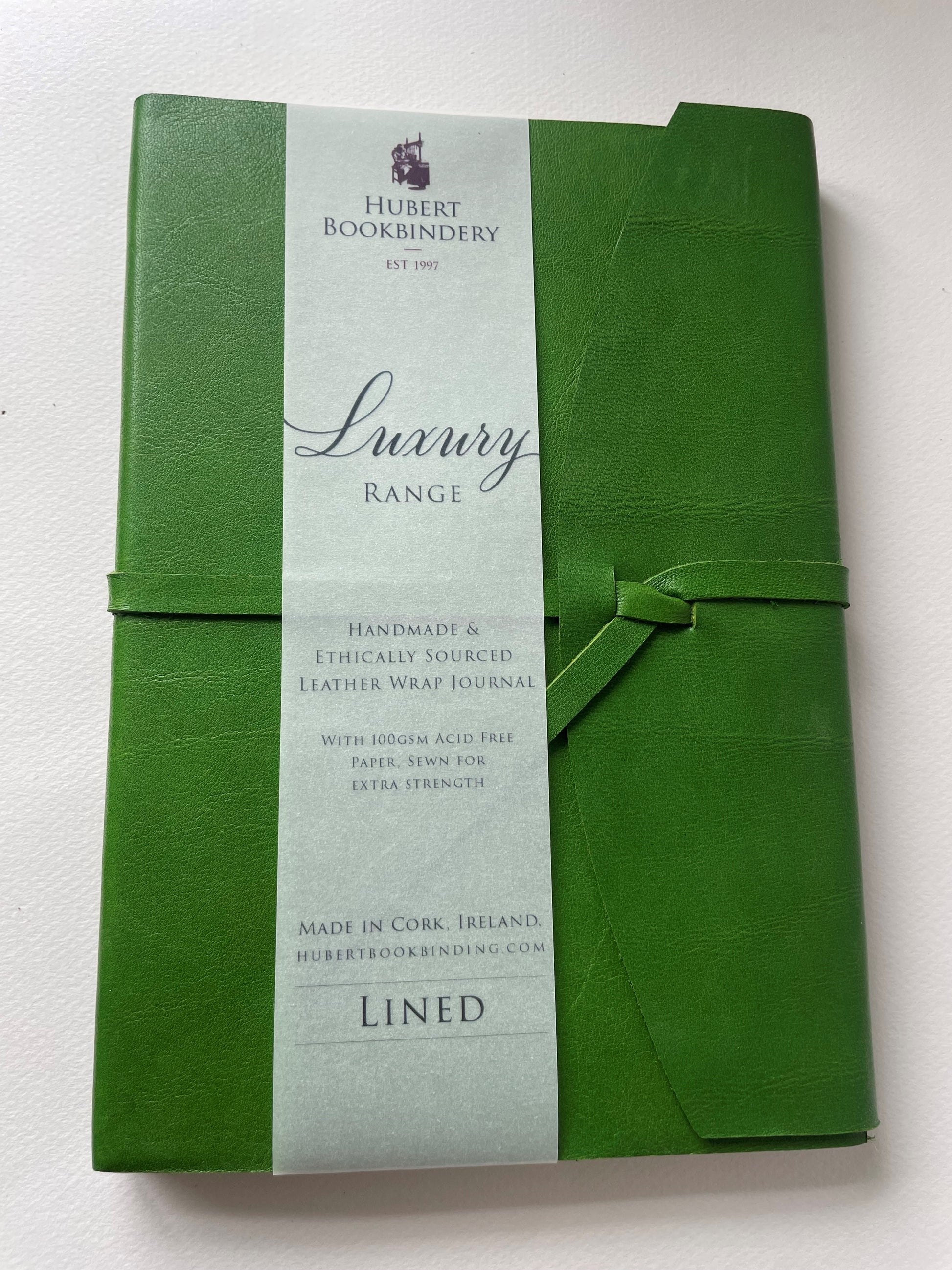 a green leather bound note book that is lined, it's handmade with a label that says Hubert Bookbindery. 