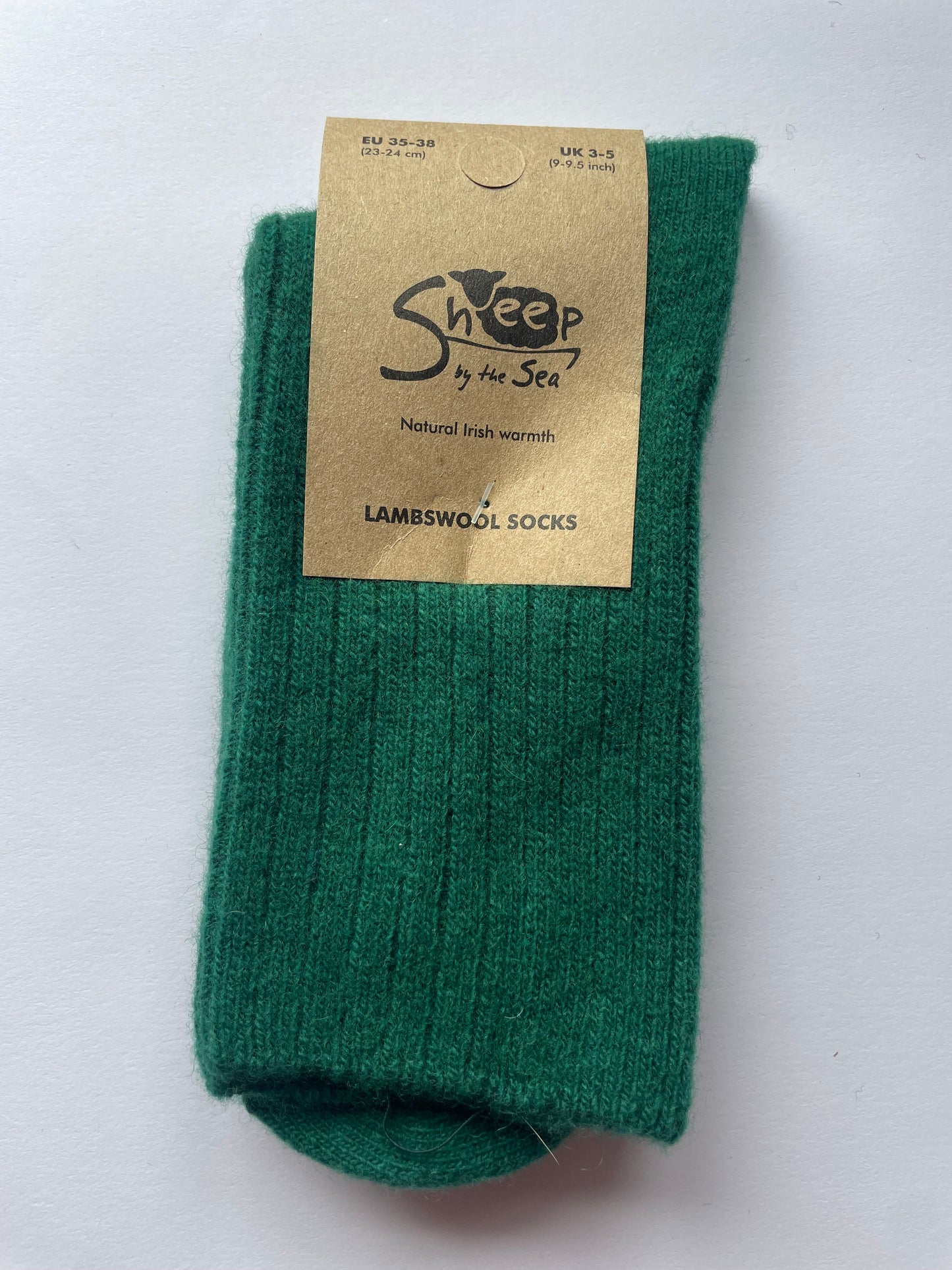 green socks with a brown label that says sheep by the sea, natural Irish warmth, lambs wool socks. 