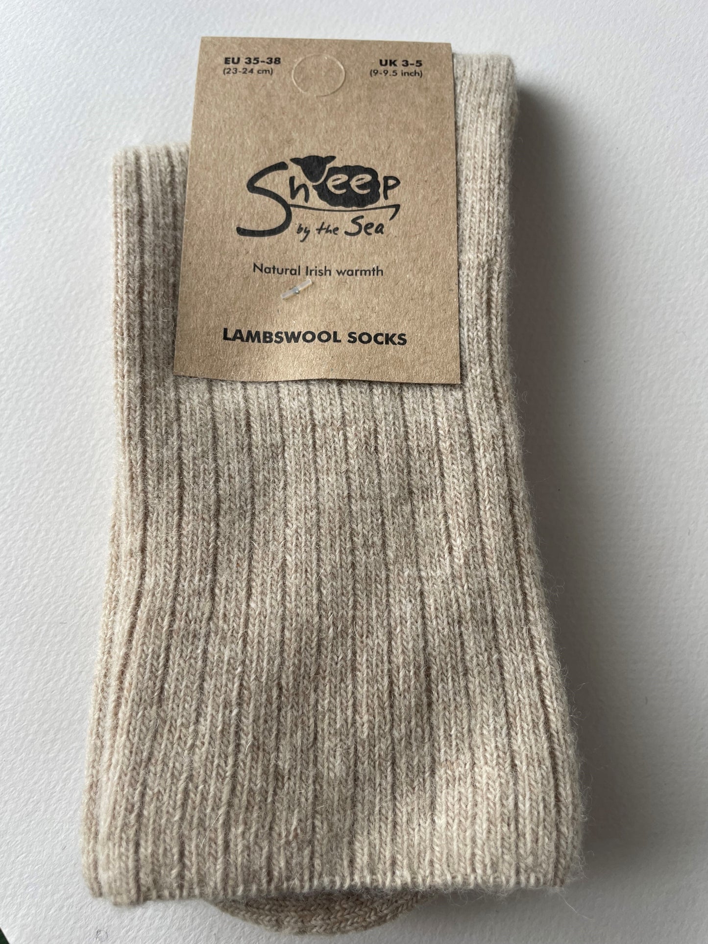 Oatmeal socks with a brown label that says sheep by the sea, natural Irish warmth, lambs wool socks. 