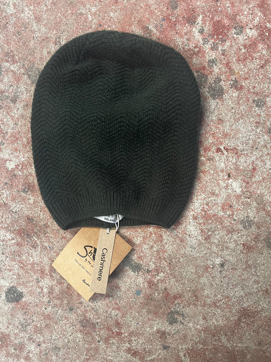 Black knit beanie with a 'Cashmere' tag on a textured surface