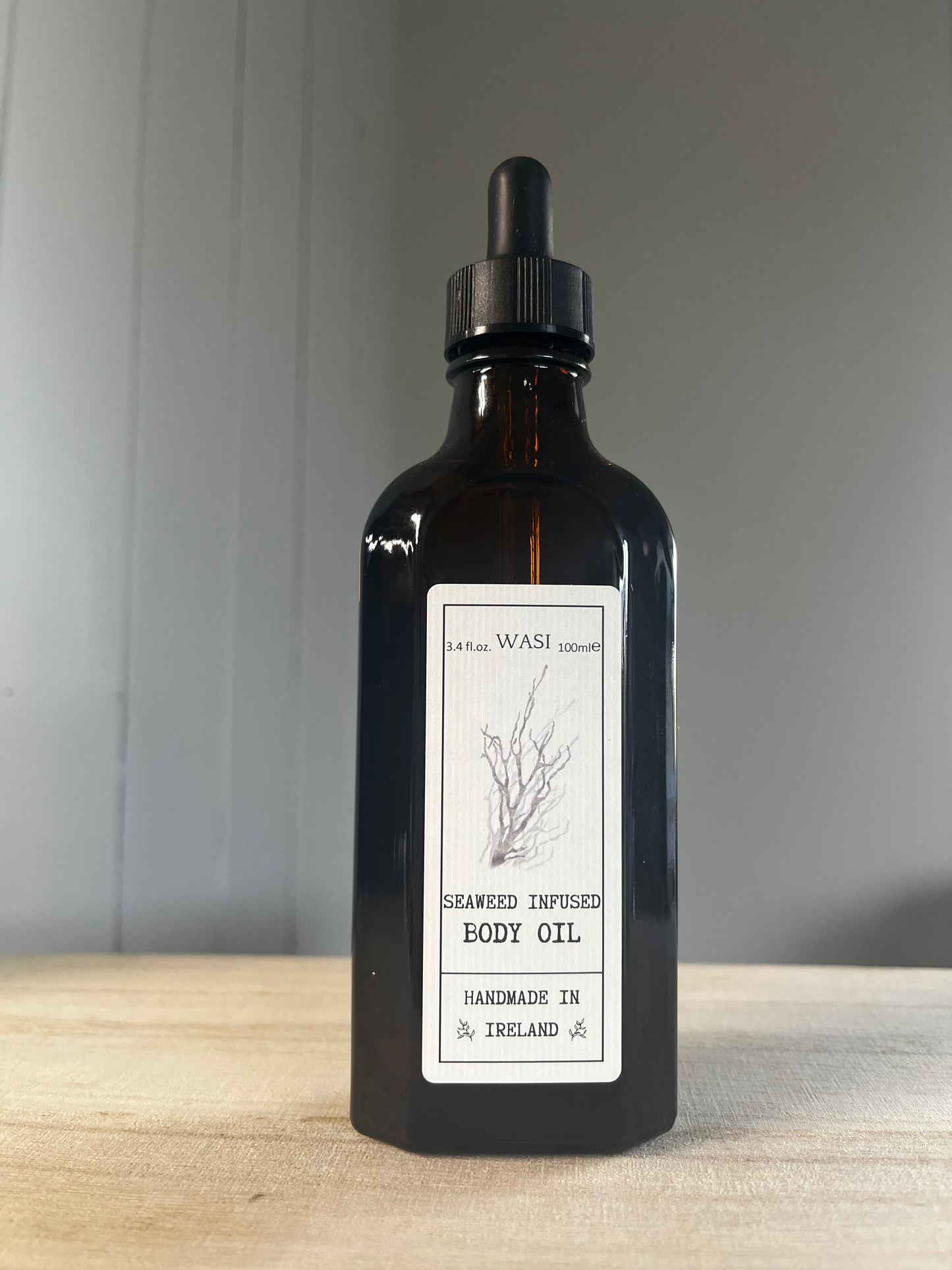 Black bottle of body oil with a label on a wooden surface