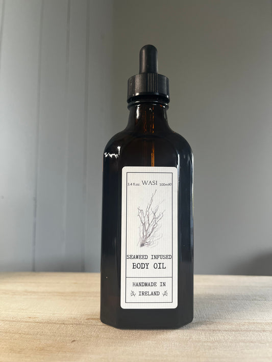 Black bottle of body oil with a label on a wooden surface